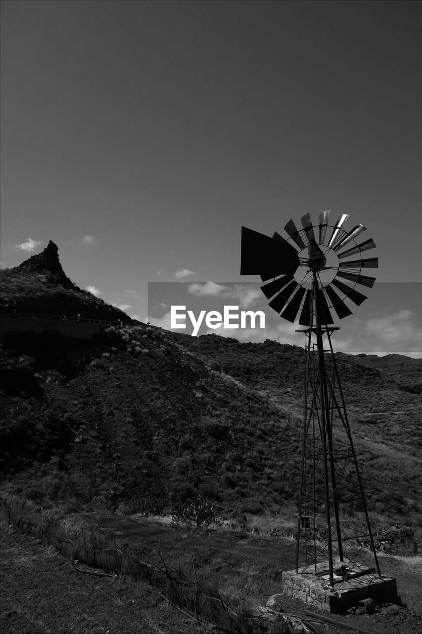 American-style windmill by mountain against sky
