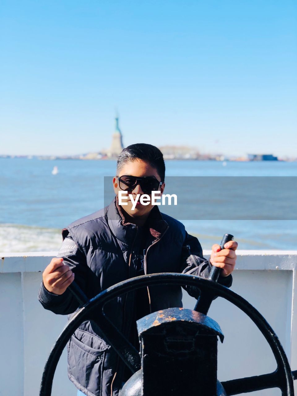 YOUNG MAN WEARING SUNGLASSES AT SEA SHORE