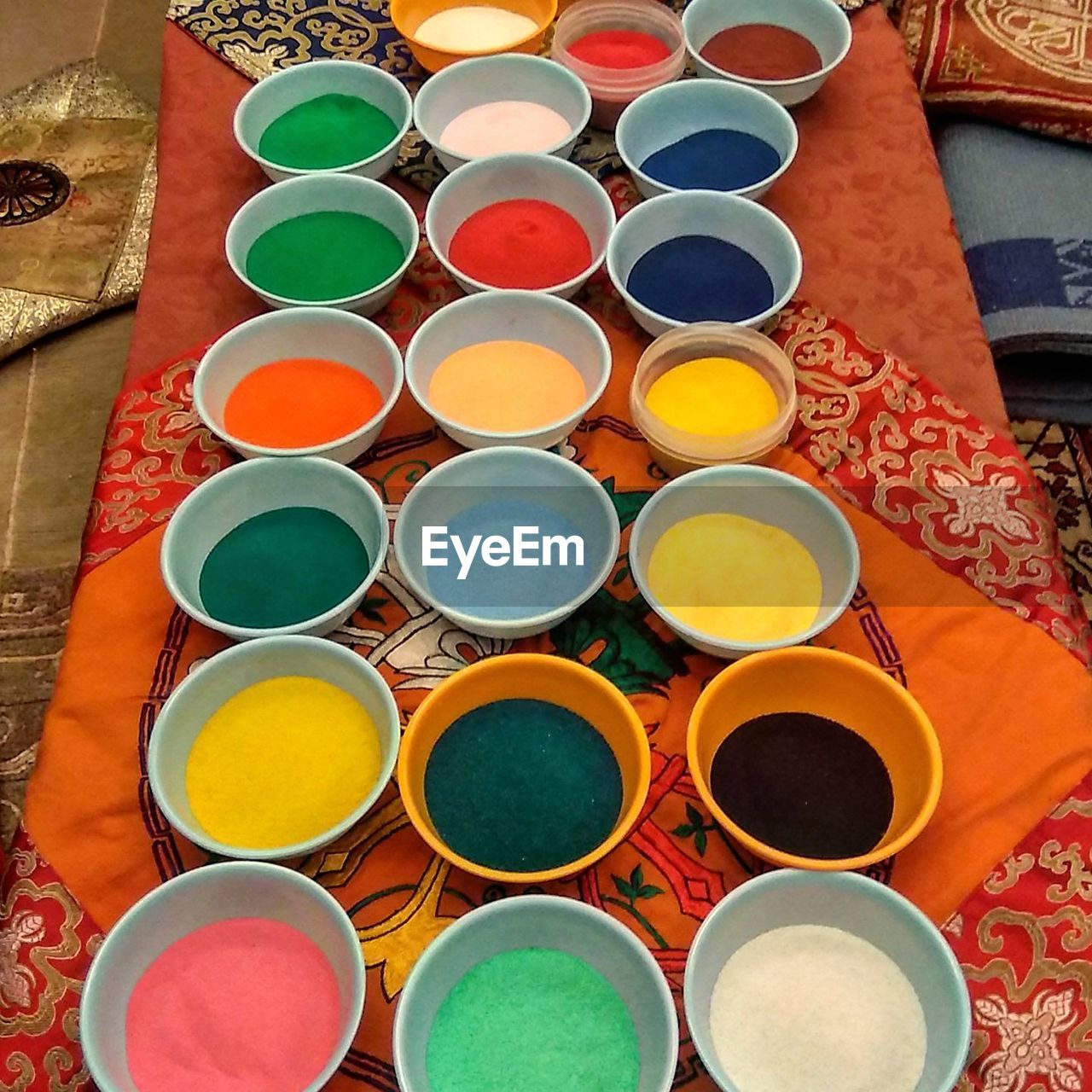 High angle view of multi colored power paint in bowls on fabric