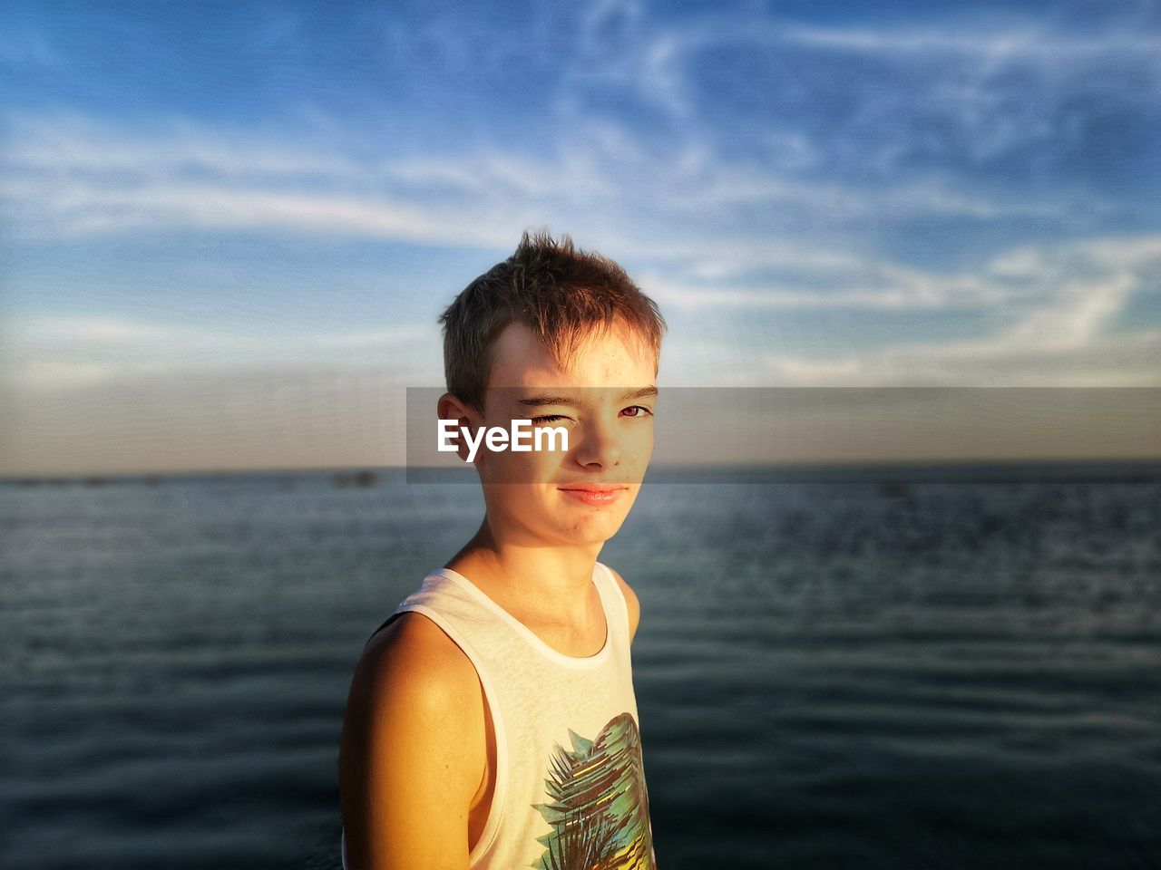 Portrait of boy winking against sea