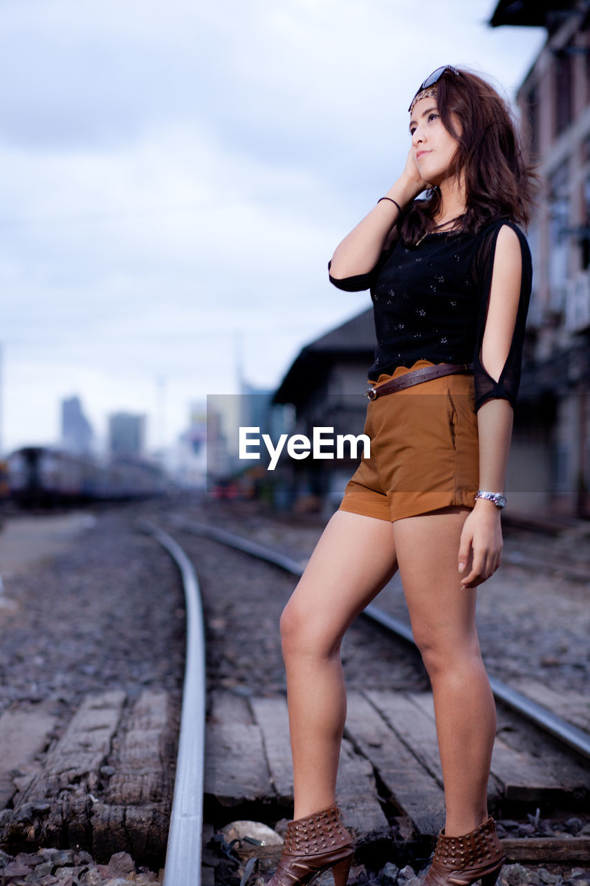 Fashionable woman standing on railroad track