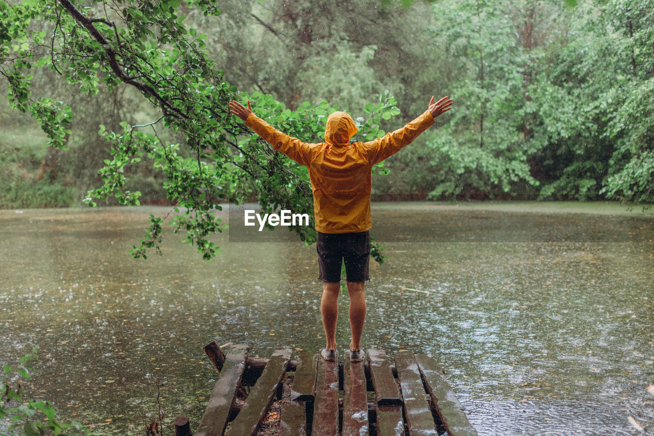 REAR VIEW OF PERSON STANDING ON WATER