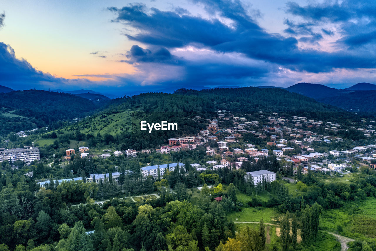 HIGH ANGLE VIEW OF TOWNSCAPE AND TREES AGAINST SKY