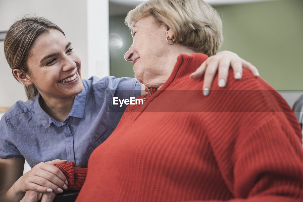 Smiling care assistant with arm around patient at home