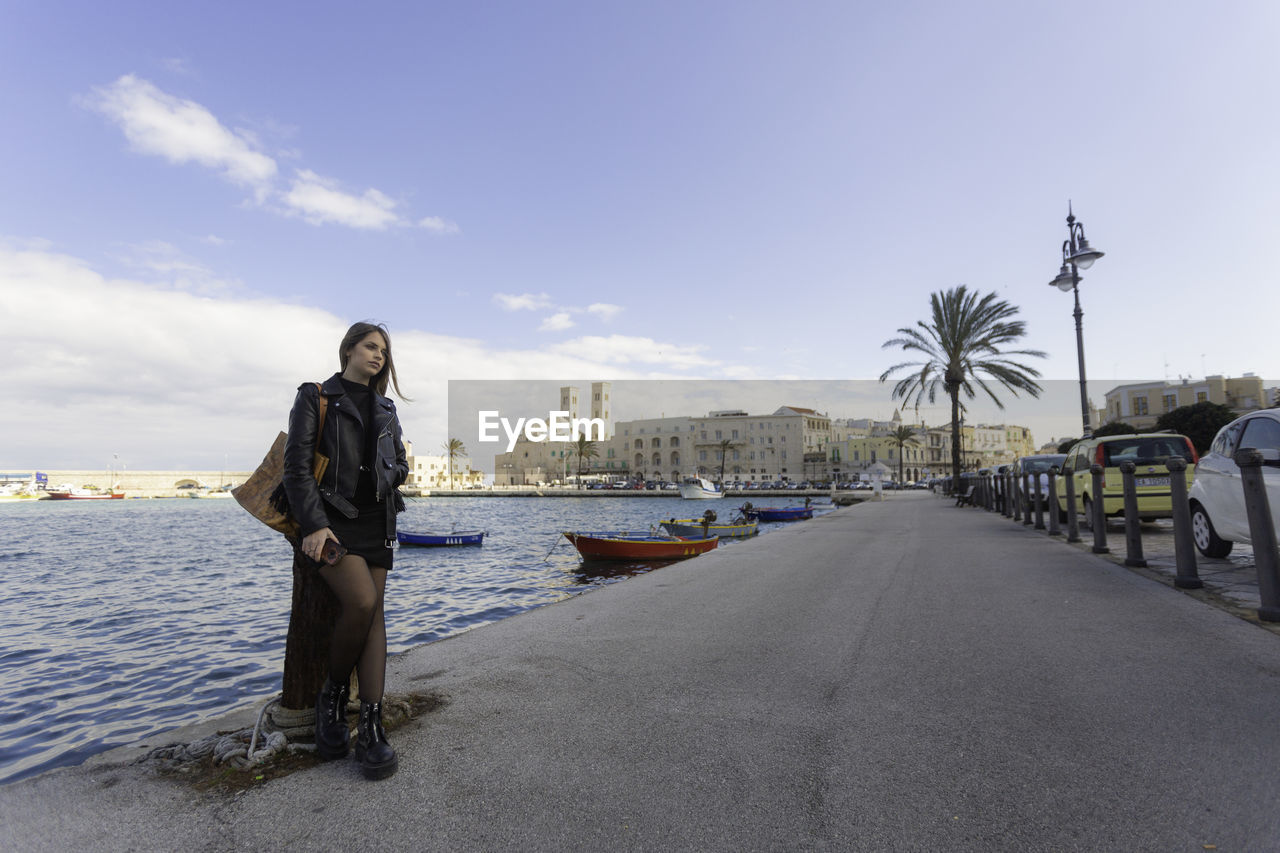 Woman standing on shore against sky in city