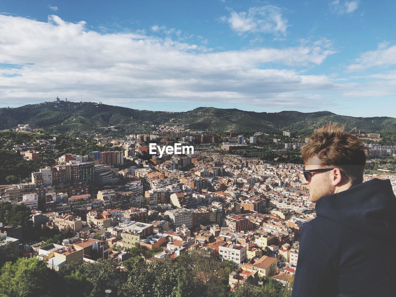 Young man looking away against townscape