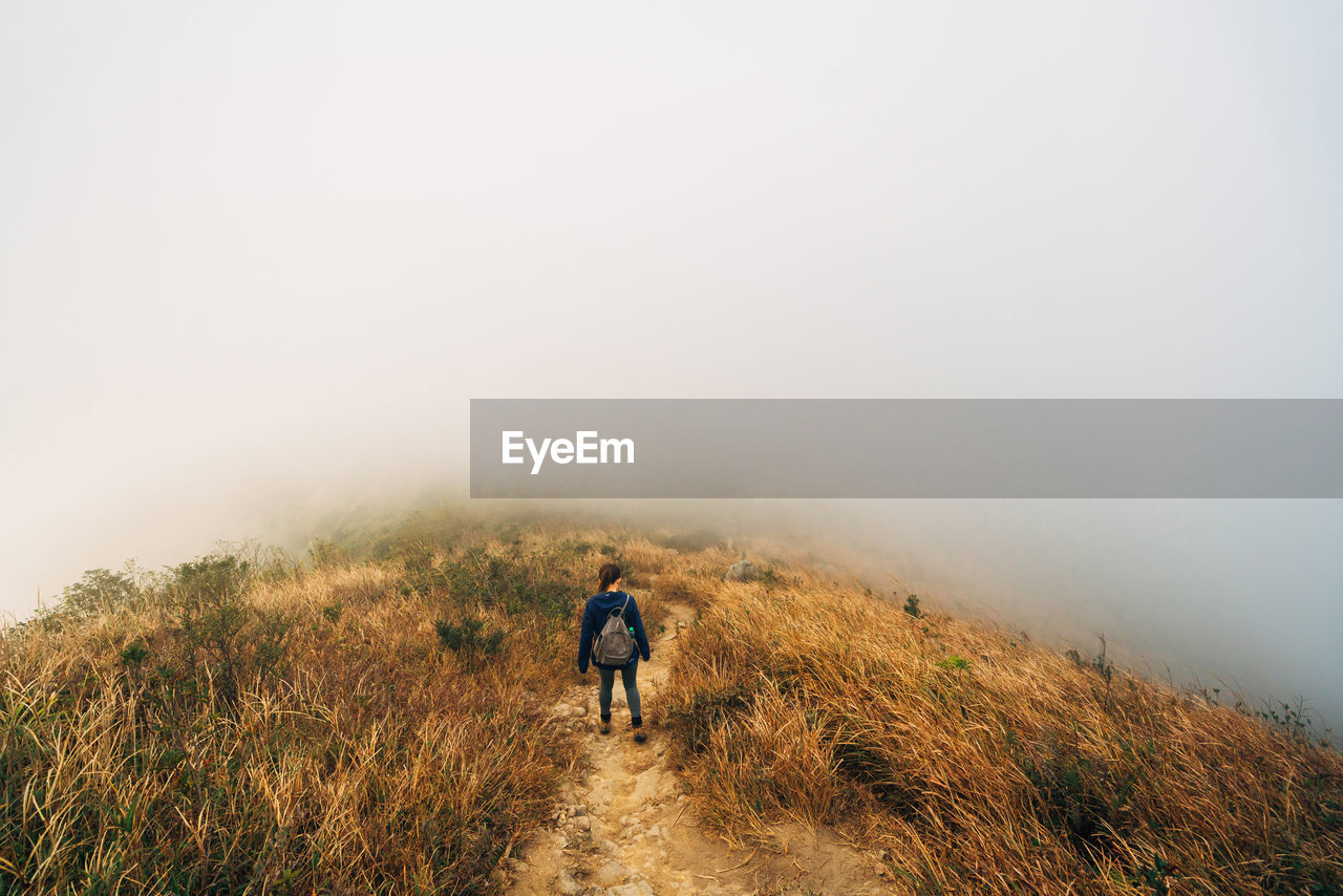 Rear view of woman walking on mountain against sky