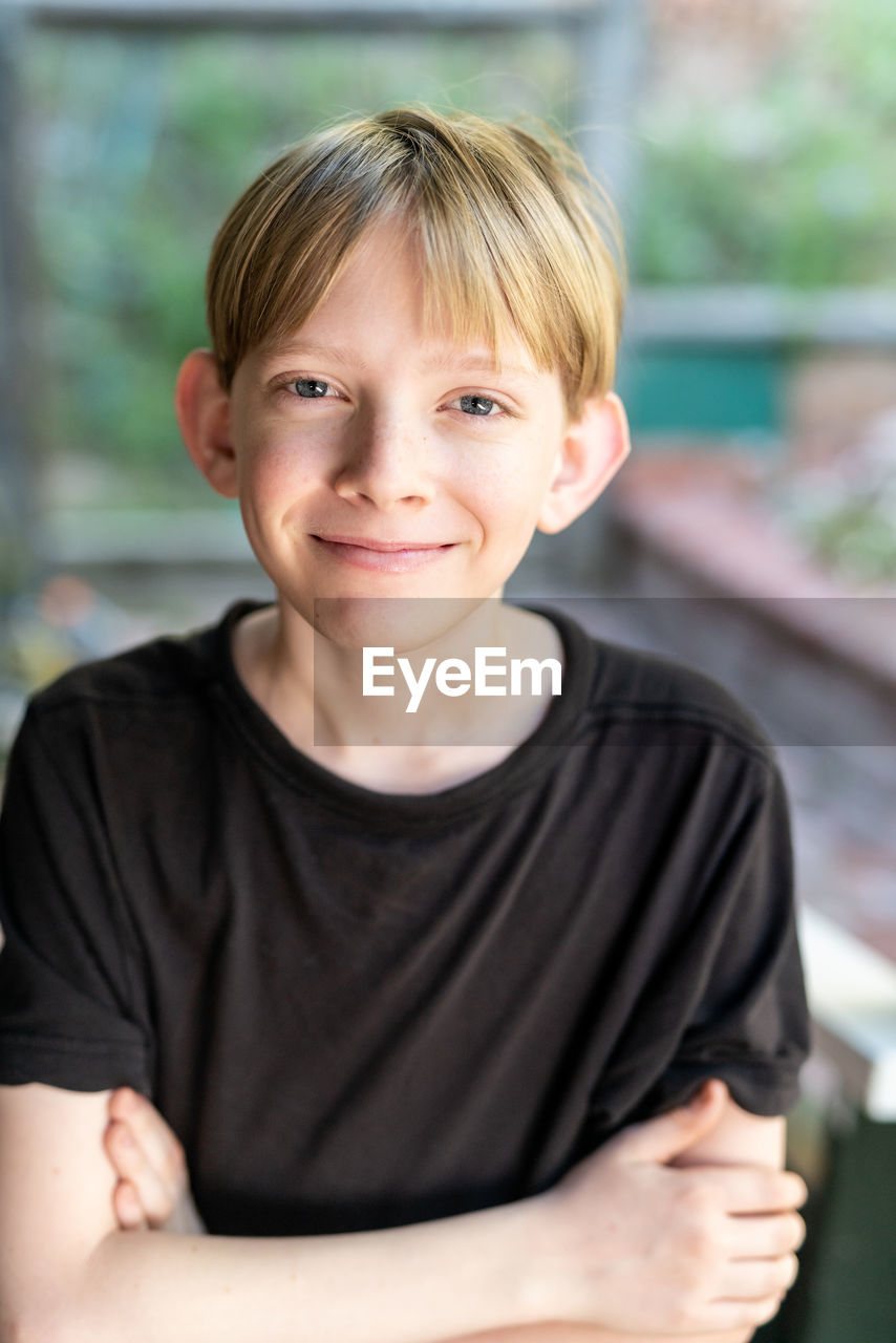 Candid portrait of tween boy smiling and looking at camera outside