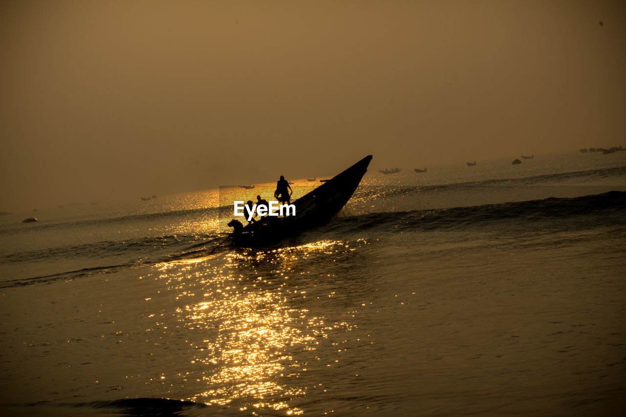 Silhouette people in boat on sea against sky during sunset