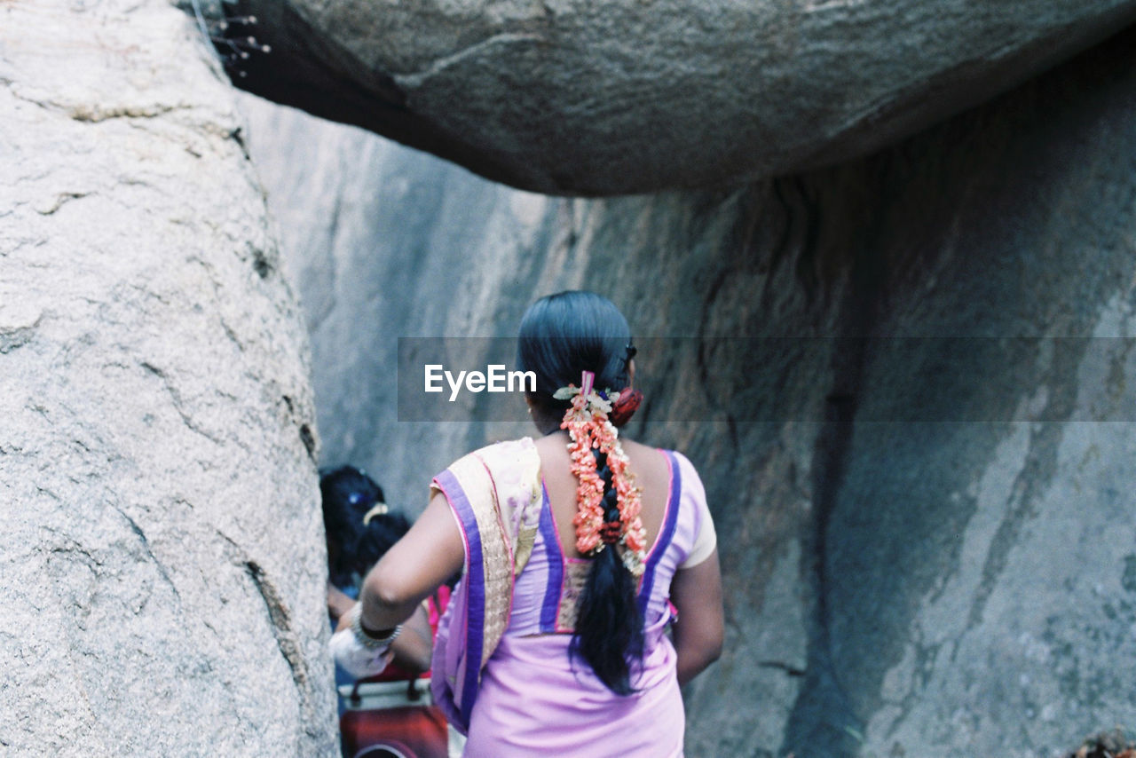 Rear view of woman wearing sari walking by rock formations