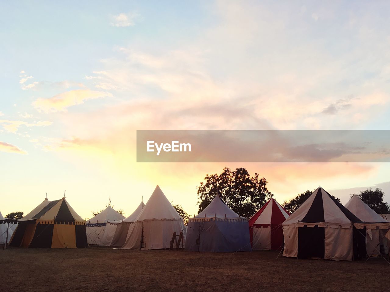 Tents on field against sky during sunset