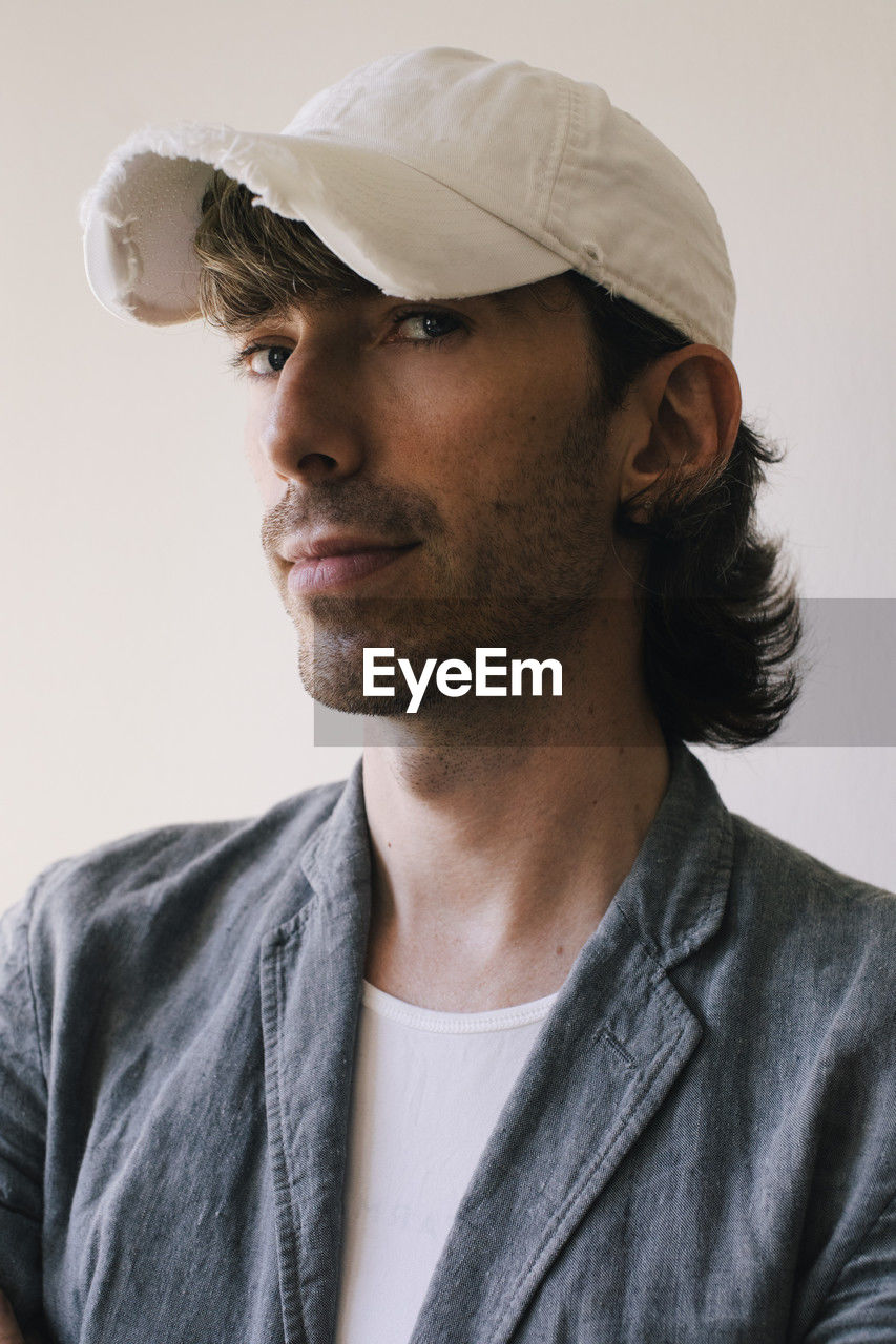 Portrait of male architect wearing cap and blazer against white wall