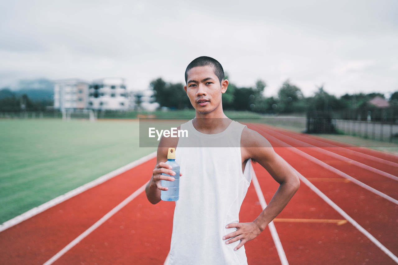 portrait of young man exercising on field against sky