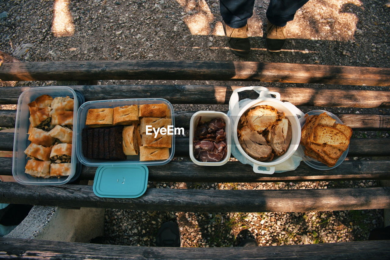 A top view photo of assorted foods on a wooden park bench