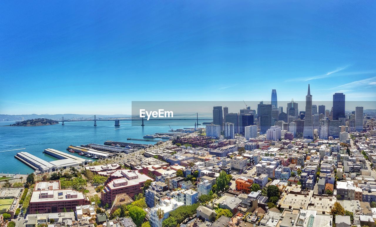 Aerial view of buildings in city against clear blue sky