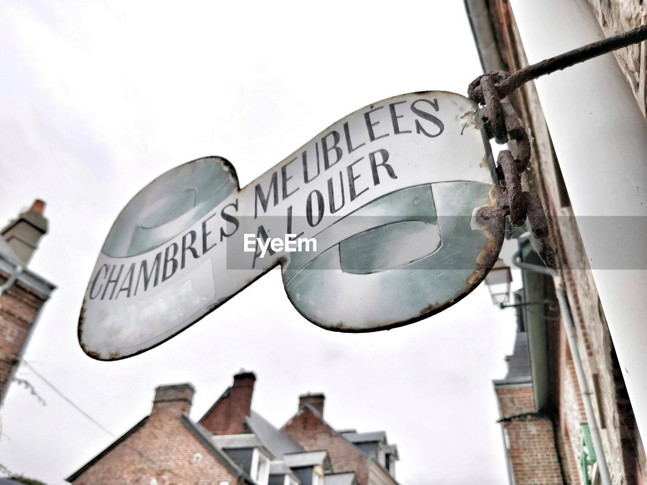 LOW ANGLE VIEW OF TEXT ON METAL SIGN AGAINST SKY