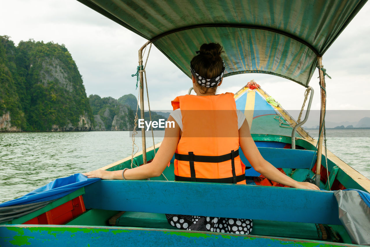 Young woman on the long-tail boat during her vacations in thailand