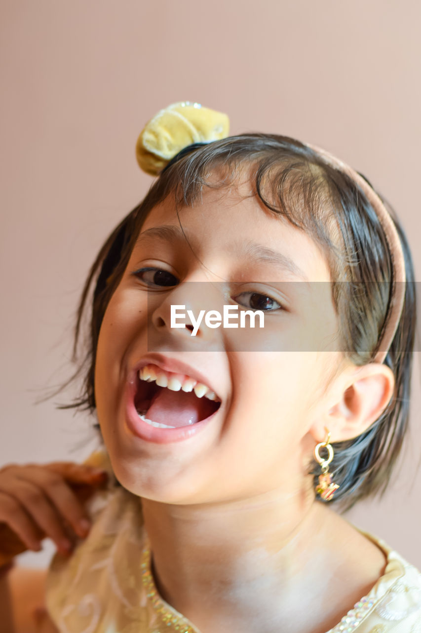 Close-up portrait of cheerful girl wearing headband at home