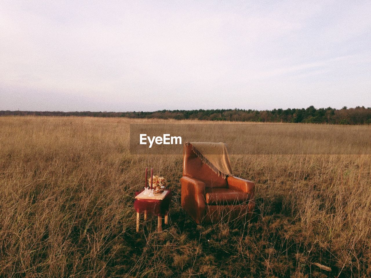 Empty chair with table on grassy field against sky