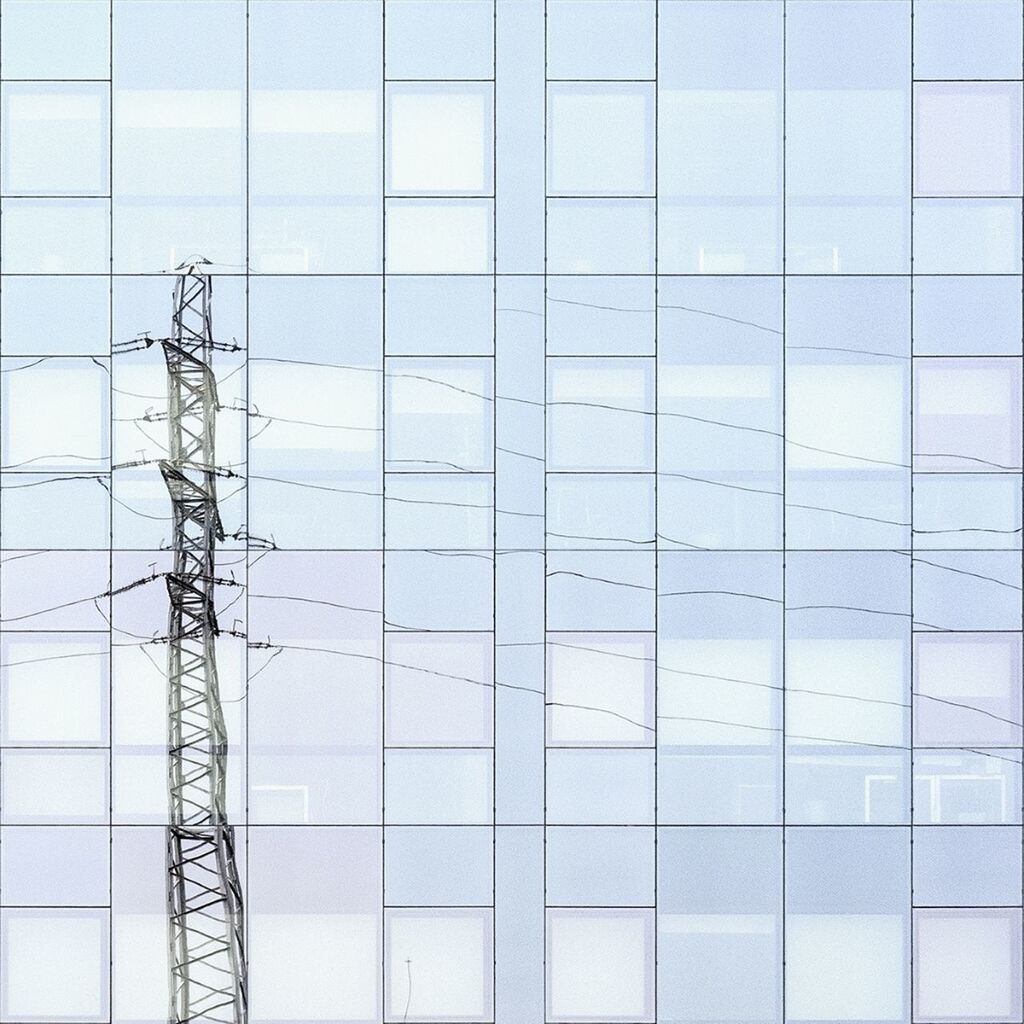 Reflection of electricity pylon in glass building