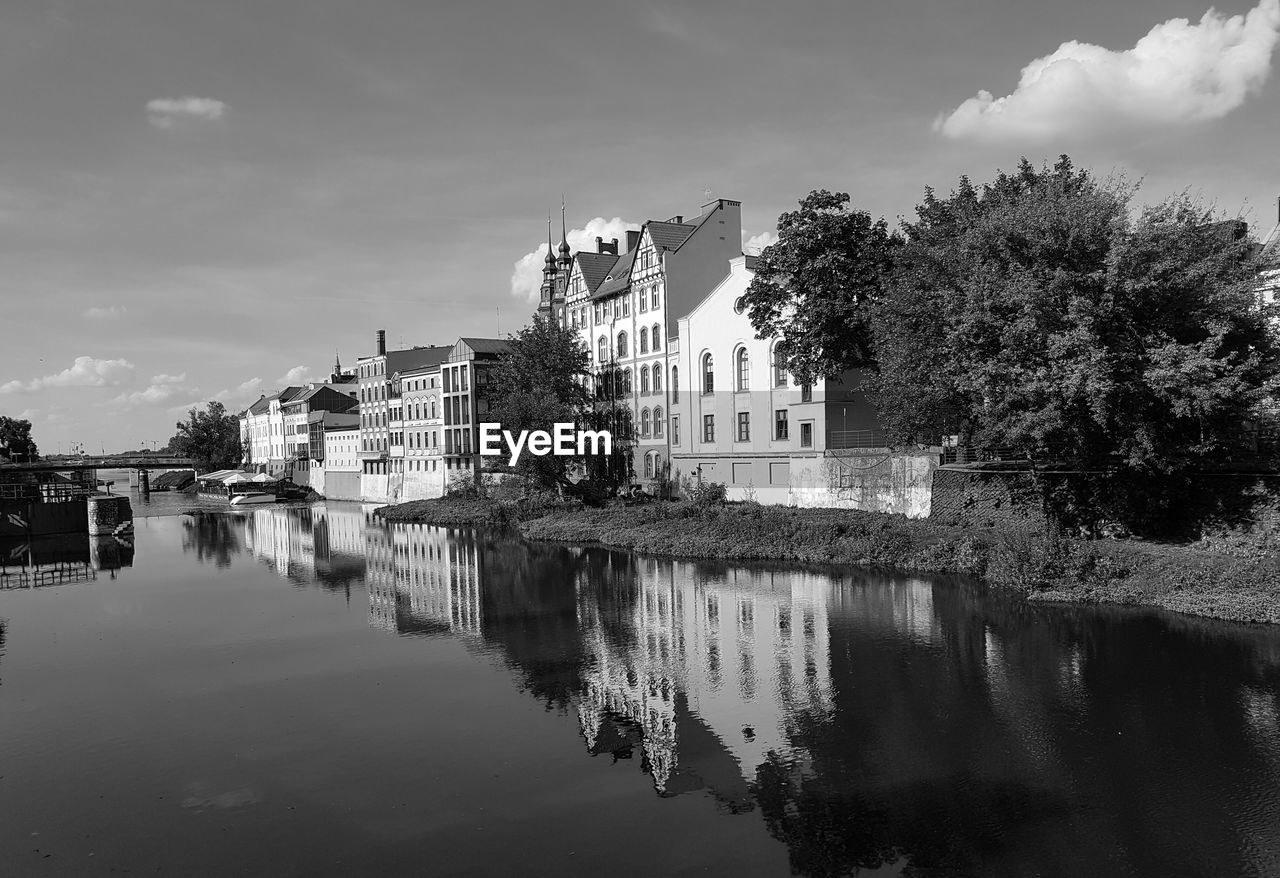 Buildings by river against sky