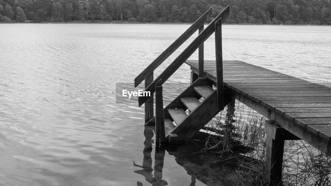 water, lake, wood, nature, black and white, tranquility, monochrome photography, day, no people, pier, tranquil scene, monochrome, beauty in nature, scenics - nature, bridge, outdoors, architecture, dock, tree, built structure, jetty, non-urban scene, plant, reflection, rippled, sky