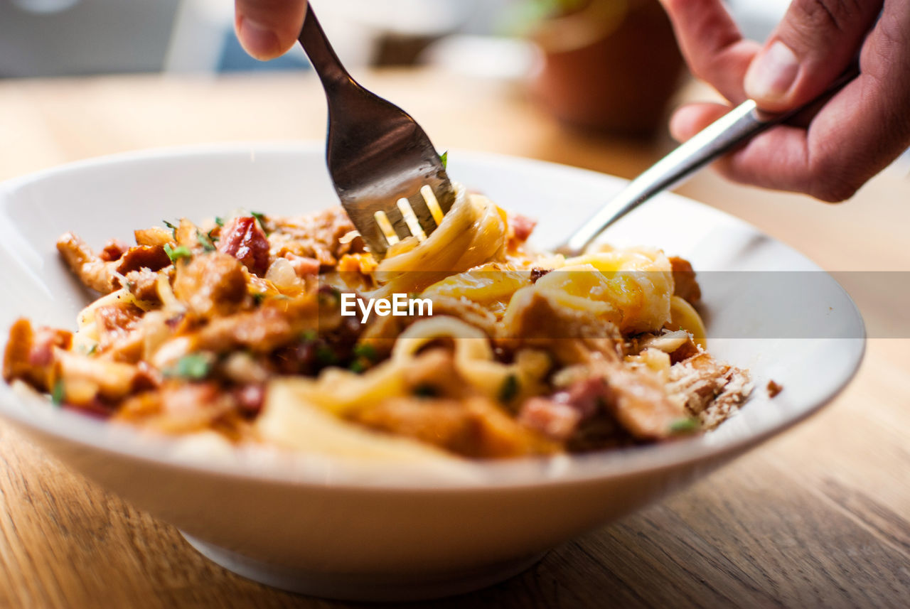 Close-up of person eating pasta dish with fork