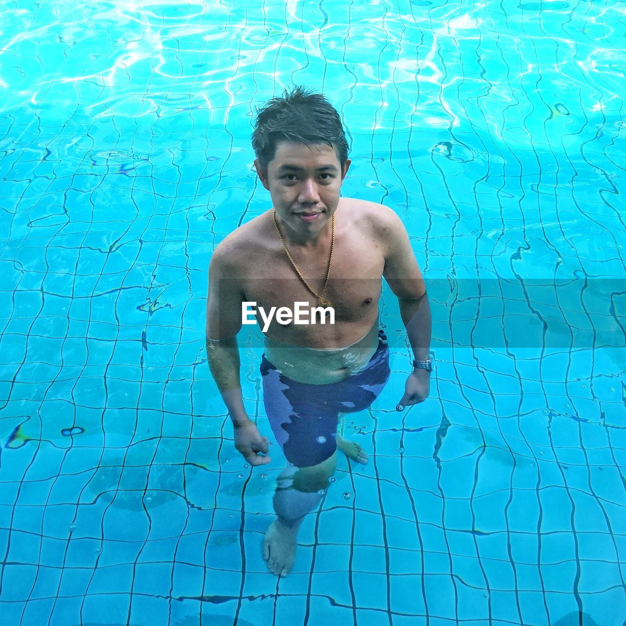 Portrait of shirtless man standing in swimming pool