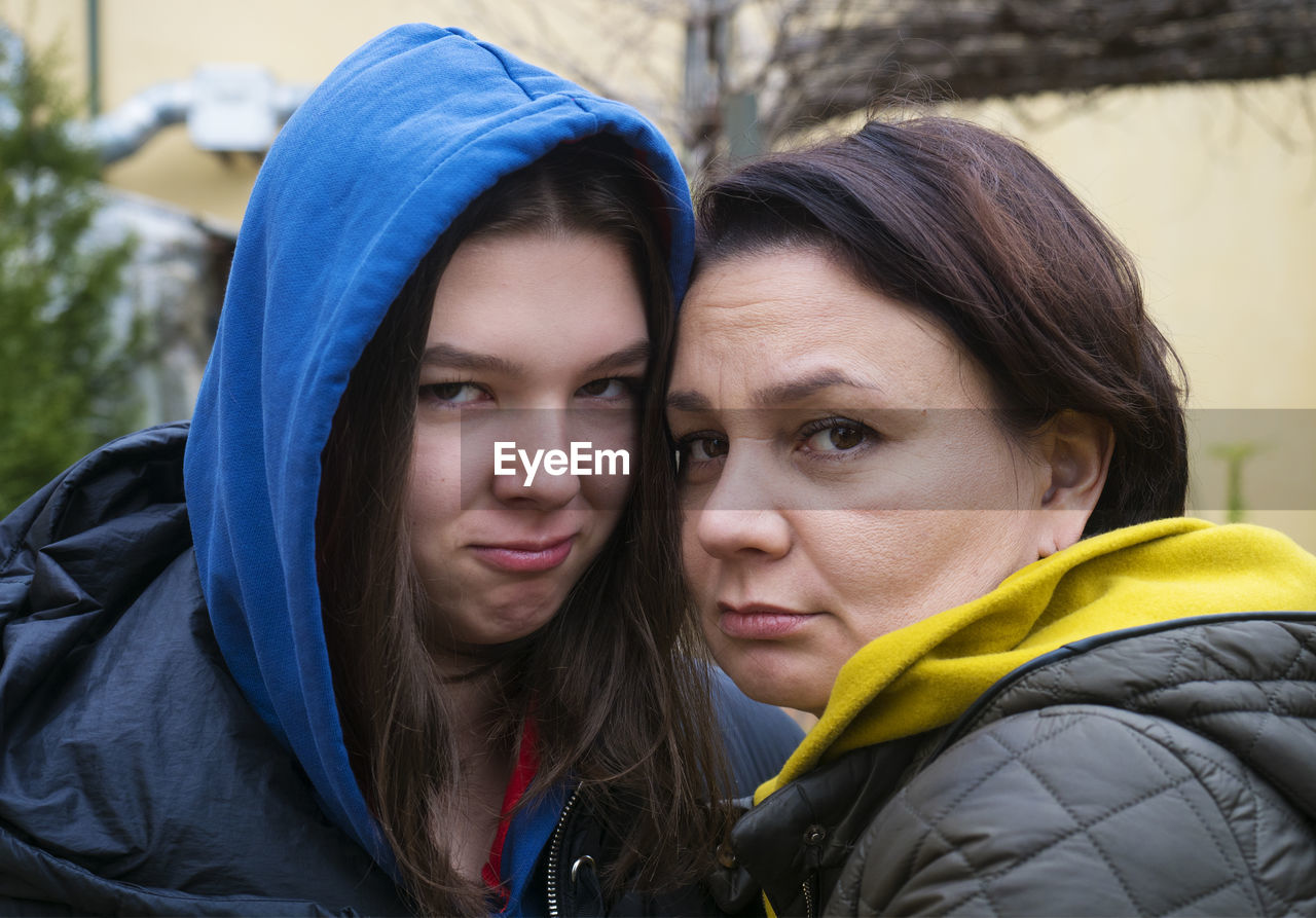 Teen girl and her mother hugging together outdoors