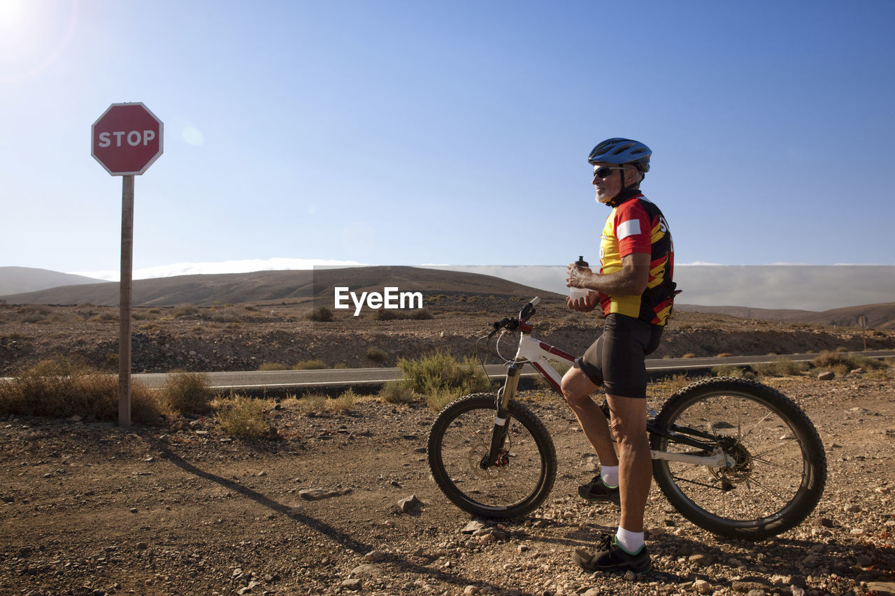 Spain, canary islands, fuerteventura, senior man with mountainbike having a rest