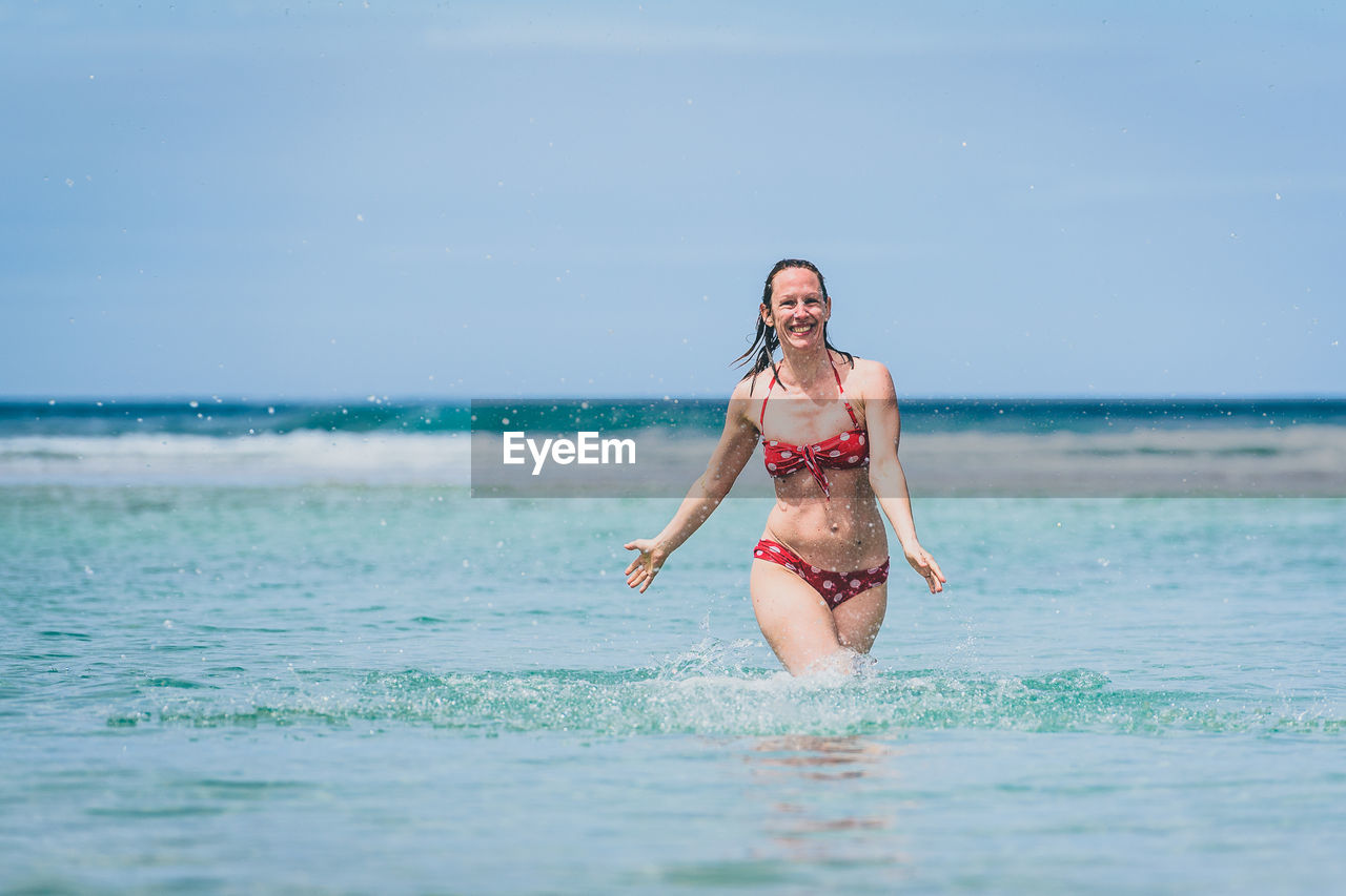 Portrait of happy mid adult woman in sea against sky