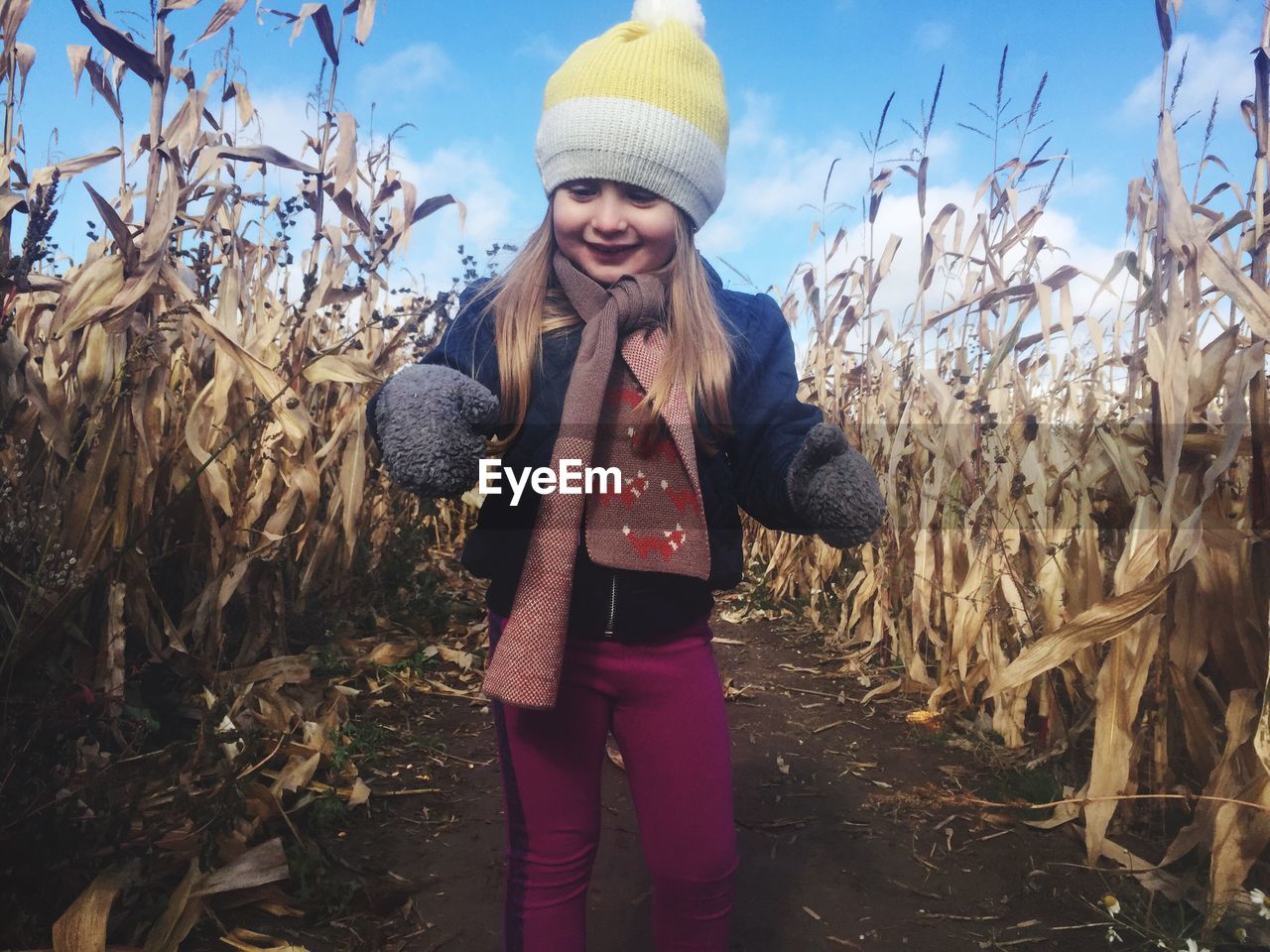Happy girl in warm clothing at corn field