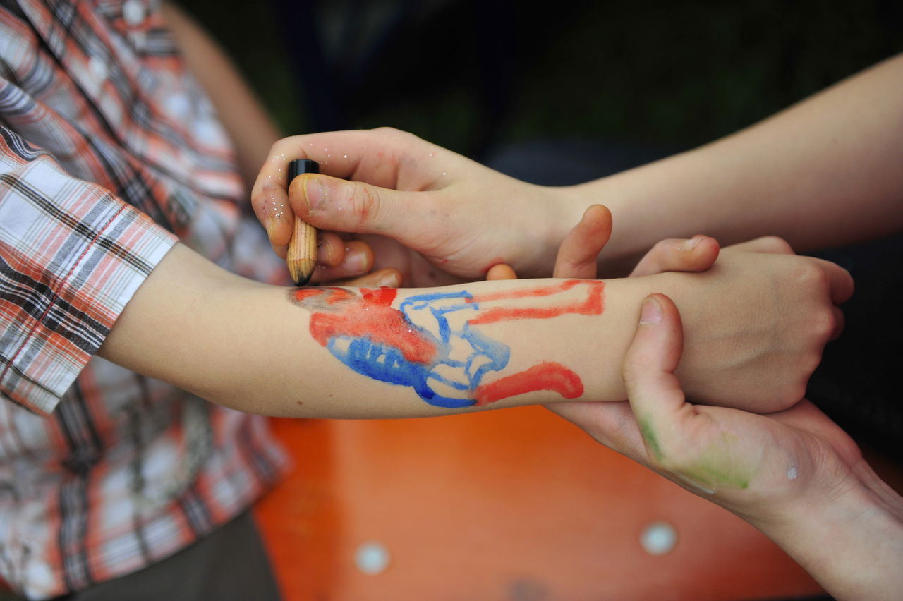 Cropped image of woman drawing on boy hand