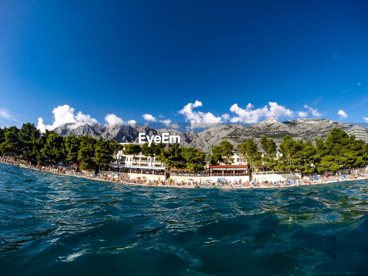 Scenic view of shore by sea against sunny sky