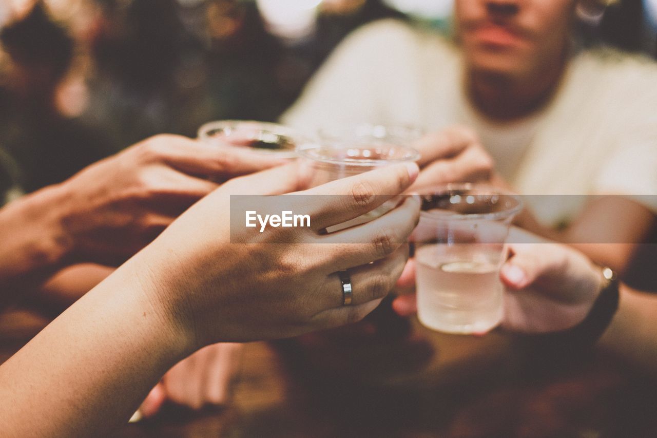 Cropped hands of friends toasting drinks in restaurant