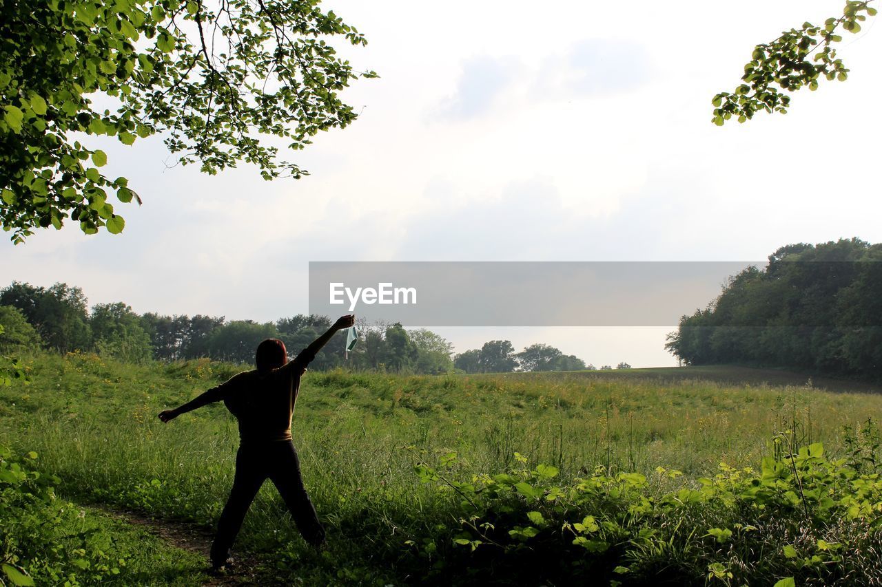 REAR VIEW OF WOMAN STANDING ON FIELD