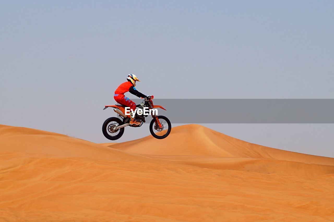 MAN RIDING MOTORCYCLE ON DESERT