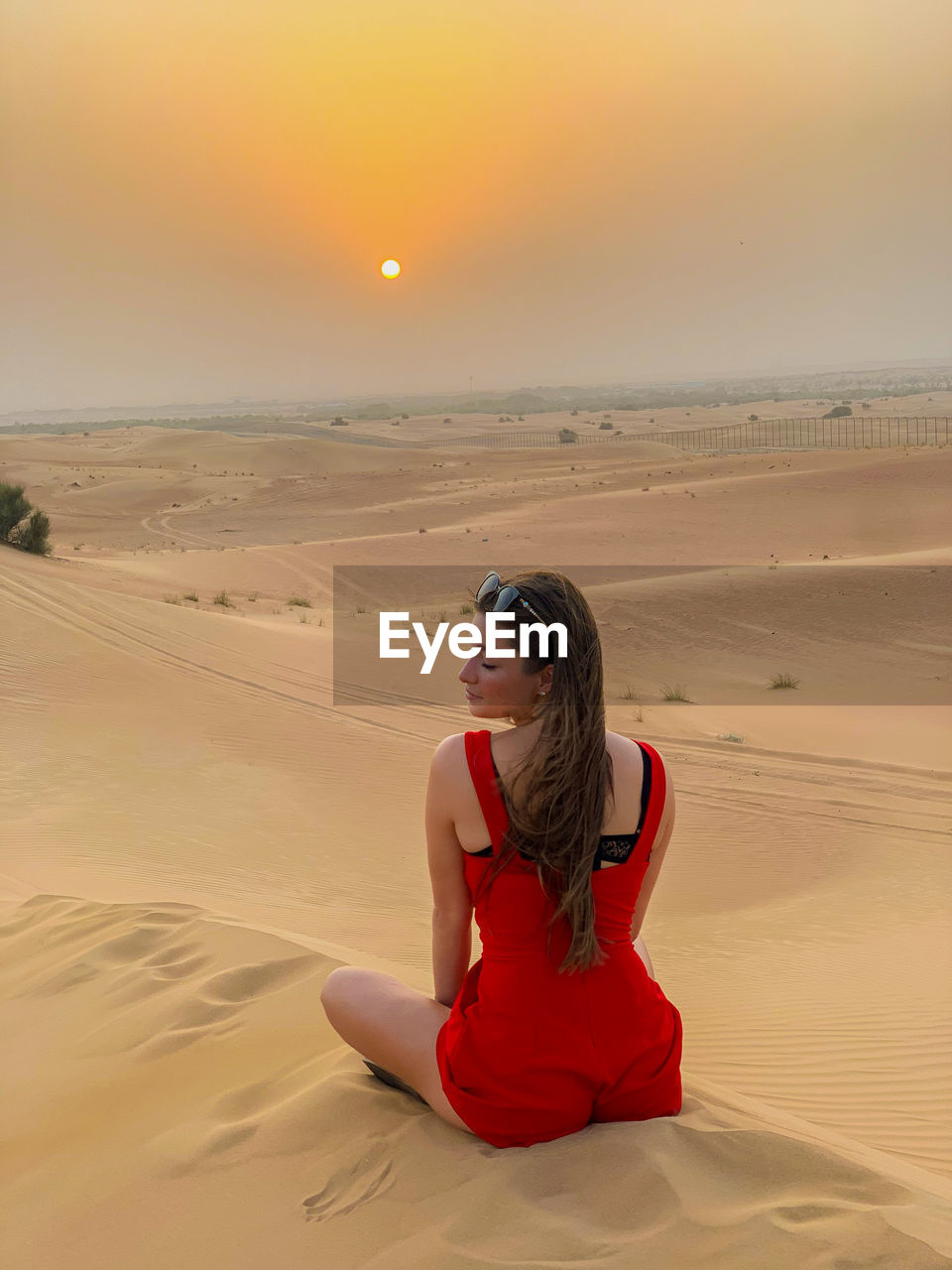 portrait of woman sitting on sand at desert