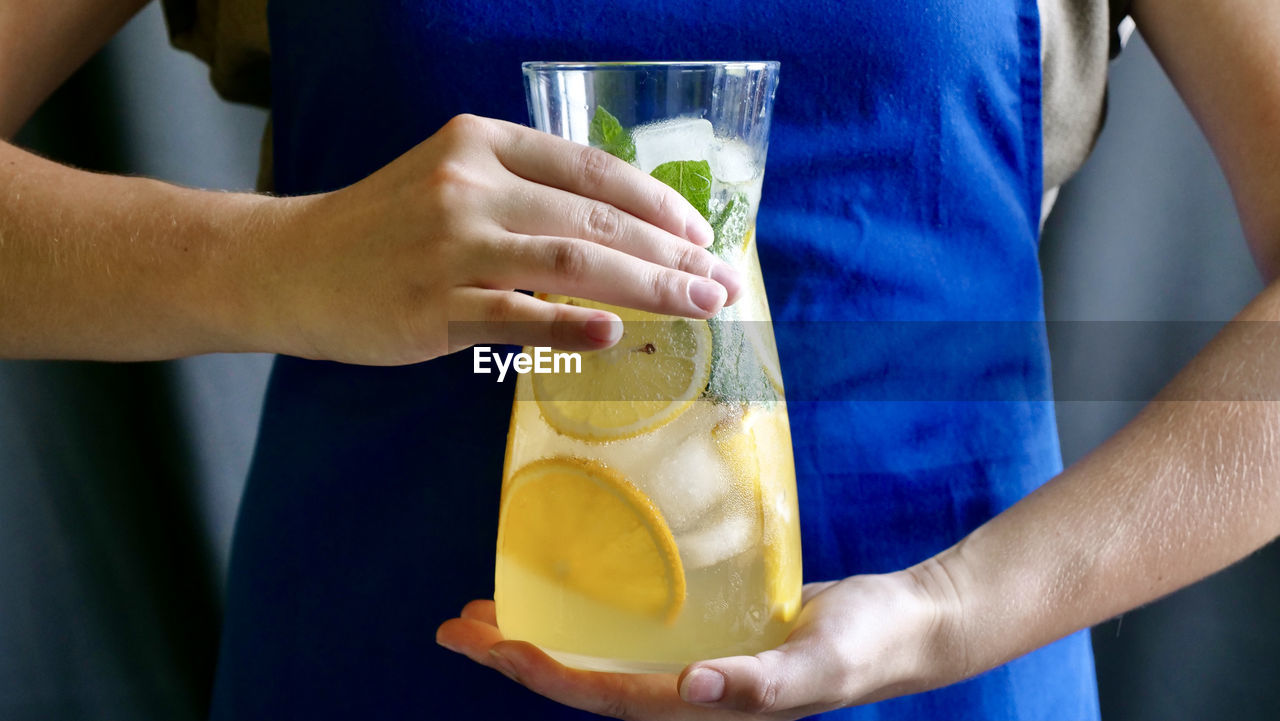 Lemon lemonade with mint, lemon and ice in a carafe.