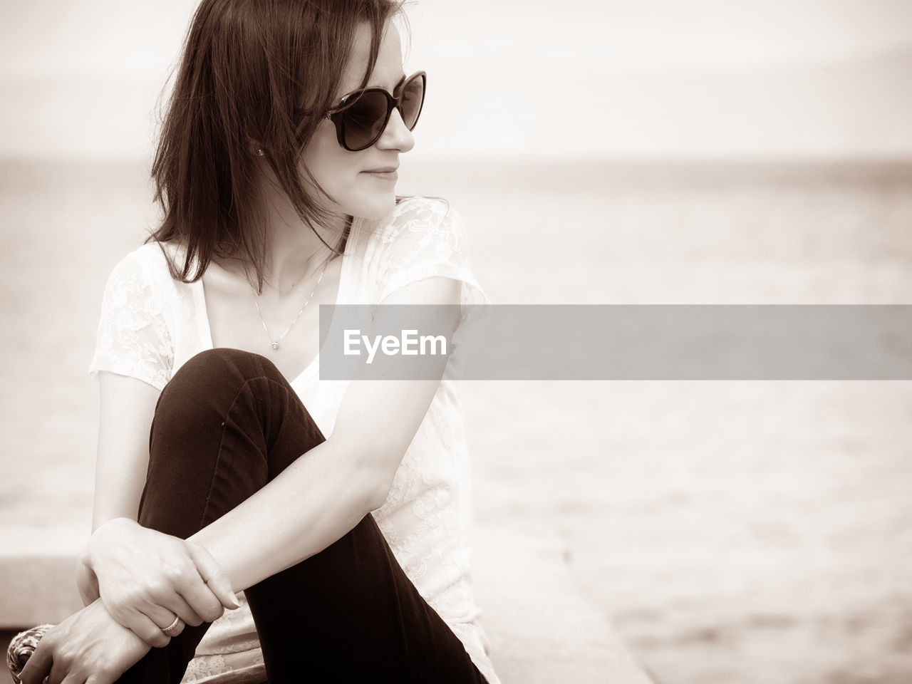 YOUNG WOMAN WITH SUNGLASSES ON BEACH