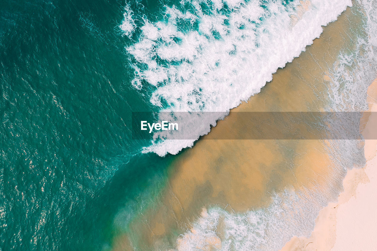 High angle view of waves rushing towards shore at beach