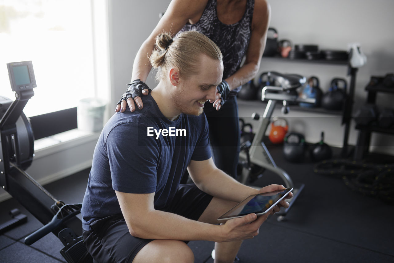 Man and woman looking at digital tablet in gym