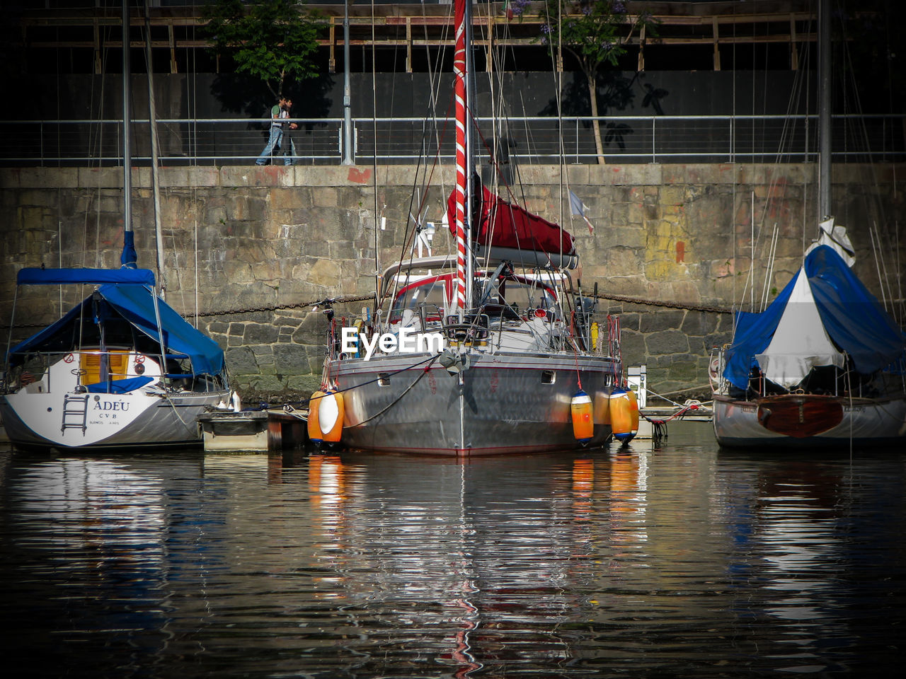 BOATS MOORED ON RIVER BY ILLUMINATED HARBOR AT WATERFRONT