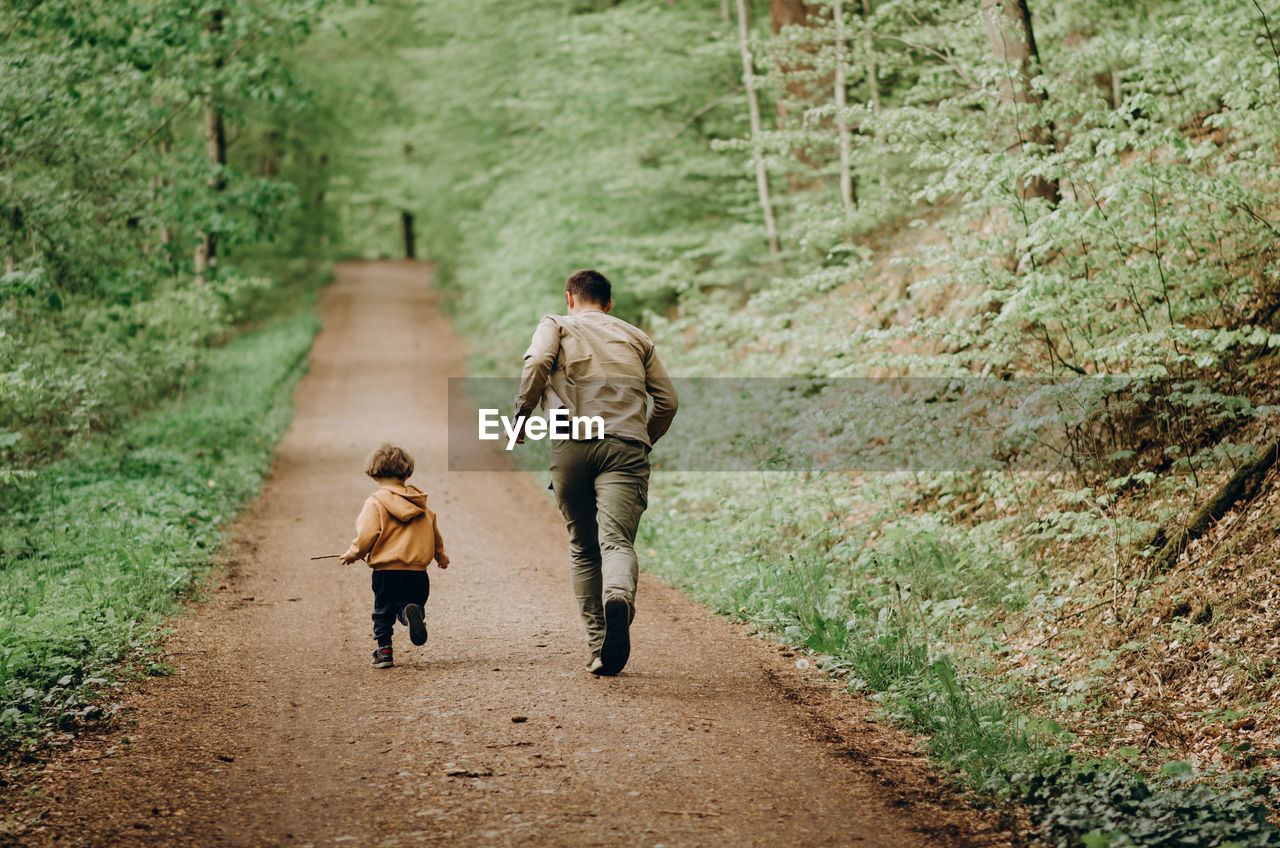 Rear view of dad and son walking on footpath