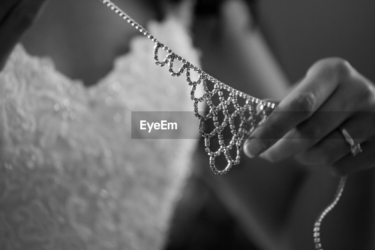 Midsection of bride holding diamond necklace during wedding