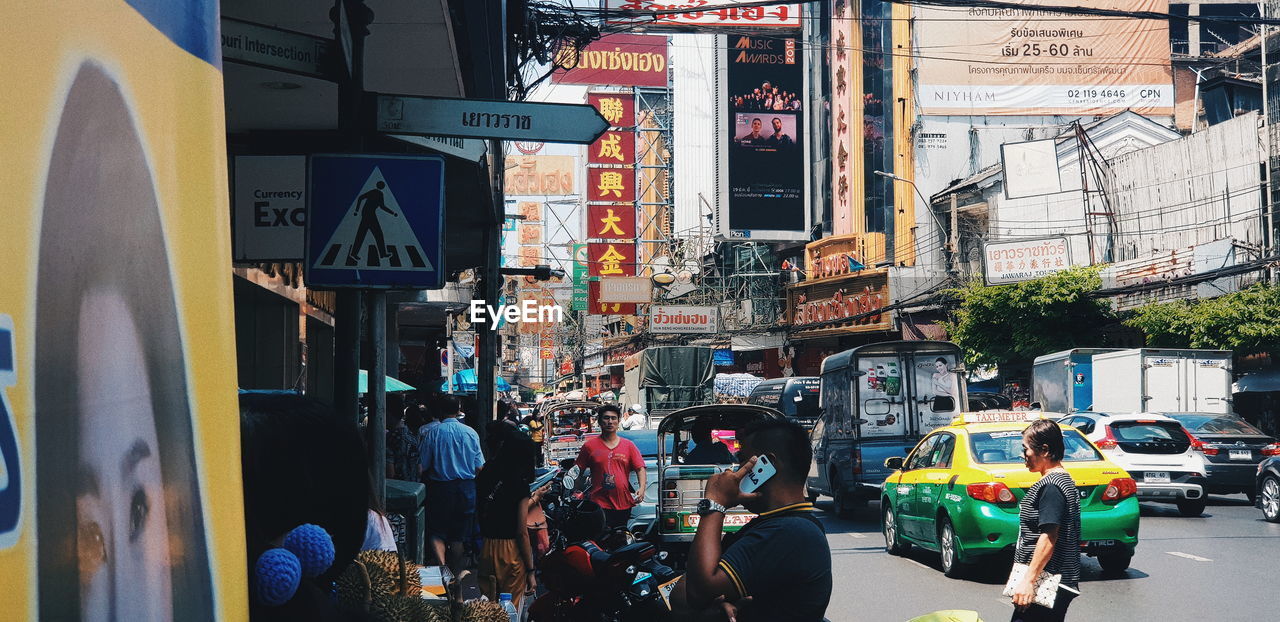 PEOPLE ON CITY STREET AMIDST BUILDINGS IN BACKGROUND