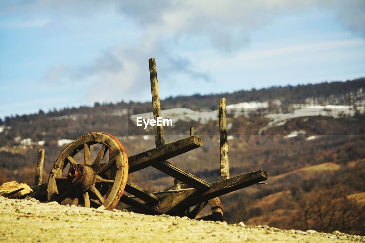 Abandoned wagon wheel on field against sky