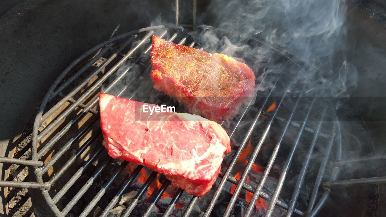 High angle view of cooking meat steak on barbecue grill