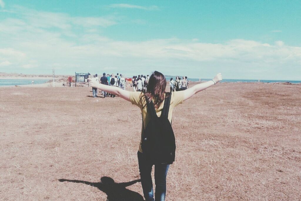 Rear view of woman with backpack arms outstretched