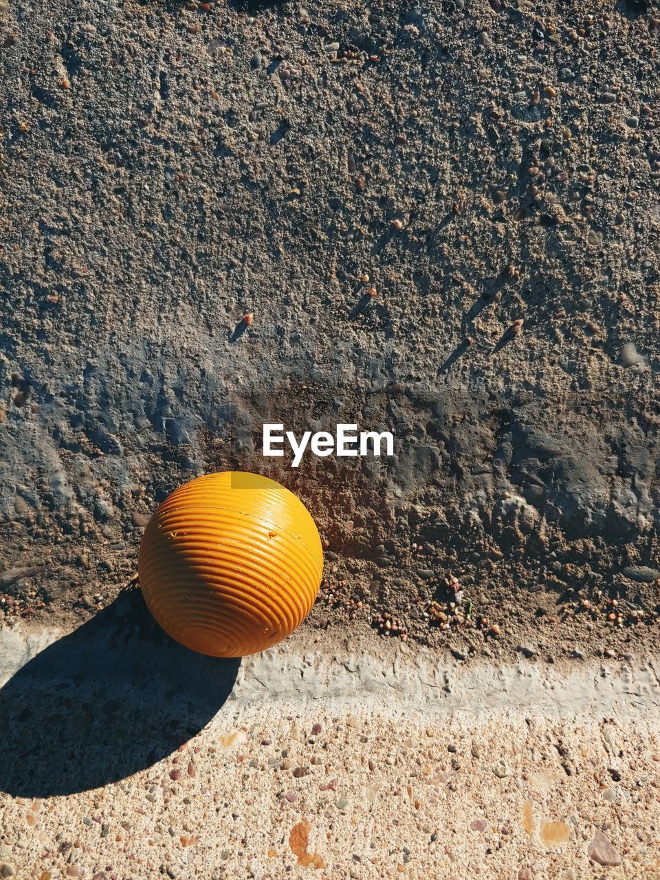 Ridged yellow ball in morning light on concrete